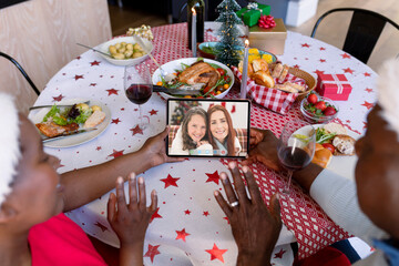 Waving african american senior couple making tablet christmas video call with mother and daughter