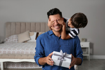 Man receiving gift for Father's Day from his son at home