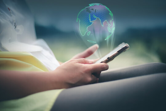 Image of a woman holding a smart phone. Technology makes it as comfortable as the whole world is in her hands. Globe sphere of planet earth displayed on a futuristic interface.