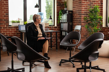 Woman psychotherapist thinking about group therapy session, sitting in circle. Specialist preparing...