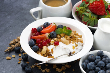 muesli with fresh berries and yogurt for breakfast on a dark background