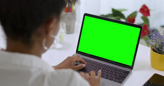 Over the Shoulder Shot of African American Business Woman Typing on Laptop, Young Female Professional Writing an Important Email From Her Home in Modern Living Room. Remote Working. Green Screen.