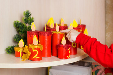 Handmade advent calendar with toilet paper tubes. Kids hands with Christmas candle craft. Seasonal...