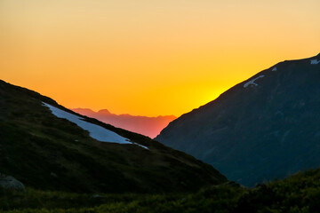 Sun setting behind a massive mountain range of Schladming Alps, Austria. The slopes are steep,...