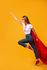 Confident woman wearing superhero cape and mask on yellow background © New Africa