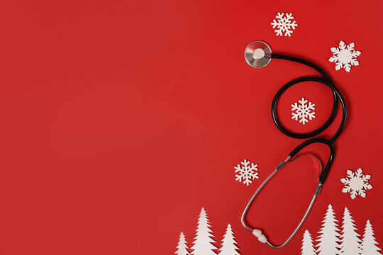stethoscope and christmas decoration on red background, copy space. winter medicine card