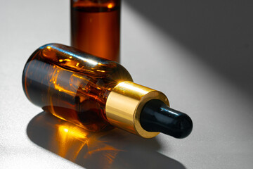 Amber glass bottles for cosmetics, natural medicine or essential oils on gray background
