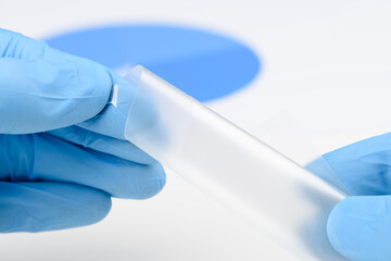 Scientist bend flexible semitransparent plastic like thin film material in laboratory. Concept of...