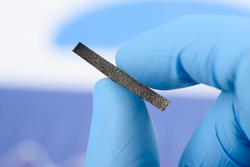Stripe of gray cellular fiber material in scientist hands. Research for material or coating with...
