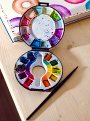 Watercolour wheel of colours and a black paint brush with painted doughnuts in the background