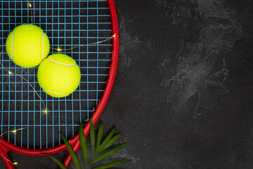 Tennis. Sport composition with yellow tennis balls on a racket with palm leaf on a black background...
