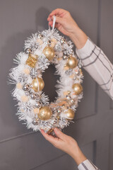 Woman hang modern rustic christmas wreath on wall