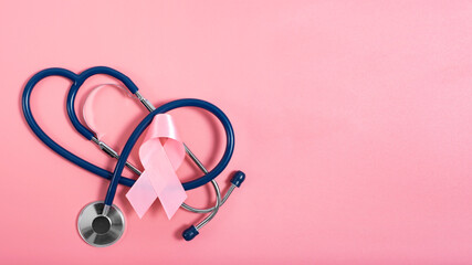 Stethoscope and pink ribbon on pink background as breast cancer awareness symbols. Flat lay view