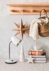 Cozy interior with lamp, christmas decorations, books,  knitted blanket in basket on the table