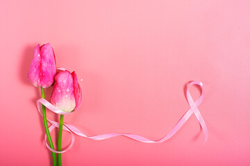Red tulips and pink ribbon on pink background as breast cancer awareness symbols