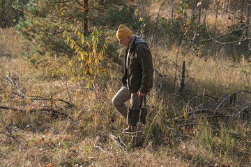 Man walking through the forest and picking mushrooms during the sunny autumn day