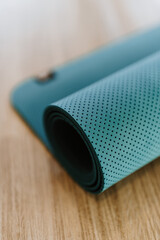 Rolled-up yoga mat on wood floor