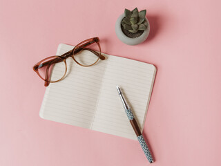 Carnet, stylo plume, lunettes et succulent sur fond rose pour trouver l'inspiration d'écrire, de...