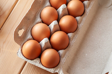 A few brown eggs among the cells of a large cardboard bag, a chicken egg as a valuable nutritious product, a tray for carrying and storing fragile eggs. A full package of eggs, an important food item