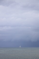 Boat sailing in the upcomming storm. Sailboat in bad weather sail at opened sea. Sailing yacht under heavy cloud sky.