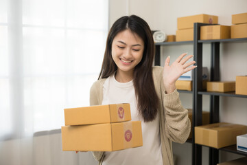 Beautiful young asian entrepreneur standing pose. Female small Business owner with box working at home. Startup freelance people with many parcel on background.