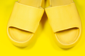 Yellow Summer Slippers on the yellow background. Pair of house indoors shoes. Minimalist, creative photo.