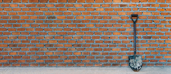 brick wall of brown color with shovel, wide panorama of masonry. Texture of old dark brown and red brick wall panoramic background.