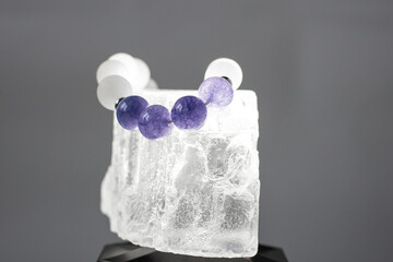 Beads from multi-colored natural stones lie on a snow-white stone, topaz and quartz