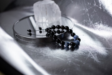 Beads from multi-colored natural stones lie on a snow-white stone, topaz and quartz, on a silver...