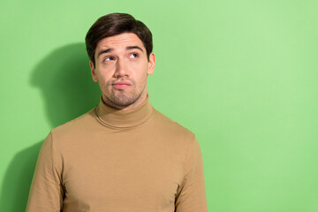 Photo of young minded man look interested empty space isolated on bright green color background
