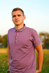 People walking. Portrait of serious young brunette man in purple polo shirt standing outdoor on...