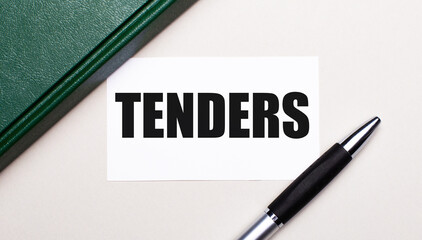 On a light gray background lies a pen, a green notebook and a white card with the text TENDERS. Business concept.