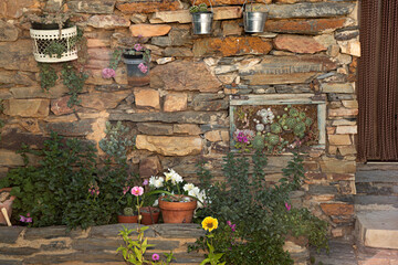 Fachada de casa de pizarra decorada con plantas y flores.