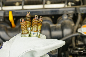 Ręka mechanika samochodowego trzymająca stare świece zapłonowe wymienione w samochodzie.