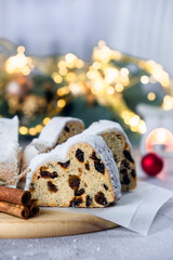 German Stollen cake, traditional European dessert with dried fruit, raisins, nuts and marzipan. Christmas pie with cinnamon and Christmas lights on background. Recipe of homemade dessert for holidays.