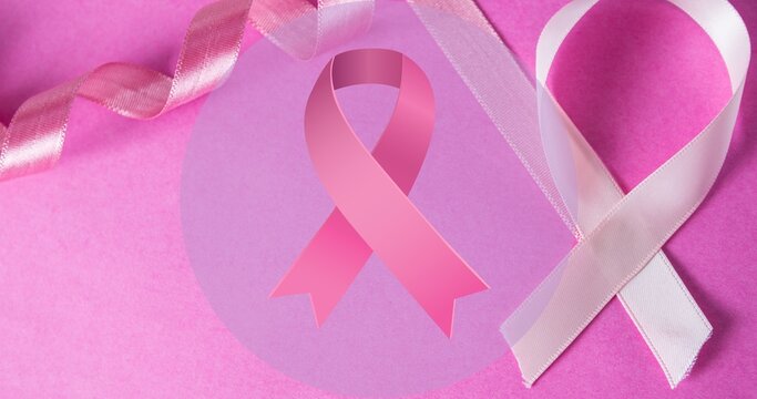 Composite image of breast cancer ribbons on pink table with copy space