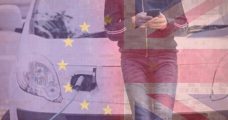 Man using smartphone waiting at electric charging station with european union and british flags