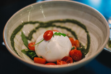Ensalada caprese con mozarella de burrata, tomates cherry y salsa pesto
