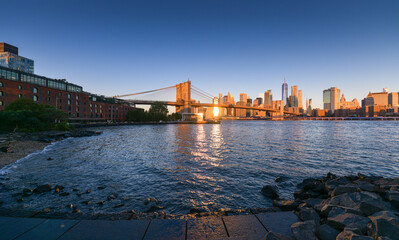 Travel to New York. The skyline of Manhattan photographed during a summer sunrise, view to Brooklyn Bridge. Landmarks of United States of America. Skyscraper office buildings.