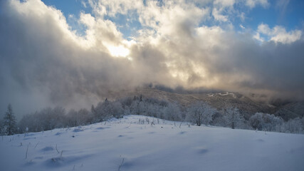 Winter landscape in the mountains with dramatic cloudy skies. Snowy mountains