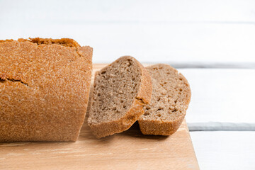 Homemade sourdough rye bread sliced on a cutting board on white table, close-up image, selective focus