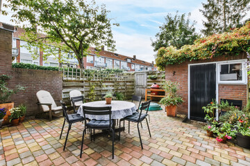 Lovely courtyard of the house with outdoor tables and chairs - obrazy, fototapety, plakaty