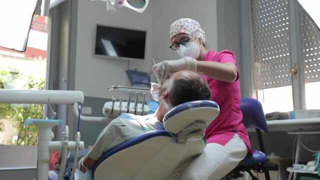 Teeth treatment session of a female dentist at her local dental office with her patient