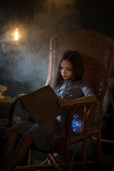 Cute little girl reads old vintage book of fairy tales in the old attic. The concept of children's fears and hopes, kid dreams, protection and mysticism. Selective focus