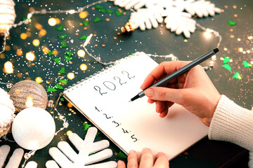 Woman's Hand writing New Year 2022 goals list