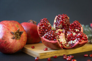 Ripe pomegranates on a dark background and pomegranate juice in a glass.