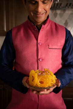 Man holding a plate of Indian dessert - jilabi