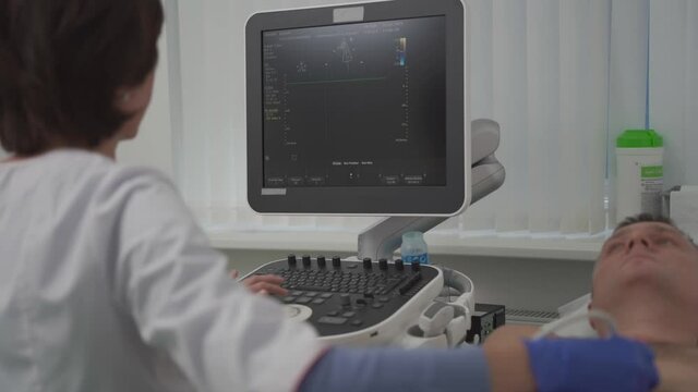 Doctor is using ultrasound machine to scan the heart of a male patient. Cardiologist makes a patient an echocardiographic test in a clinic. Patient under ultrasound examination in the hospital