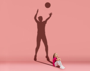 Conceptual image with kid and shadow of female volleyball player on studio wall. Dreams about sport...