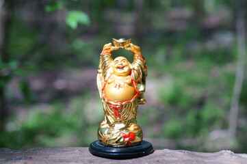 A figure of a happy smiling Buddha on a colored natural background. A religious symbol. Spiritual and personal growth. Mentor.